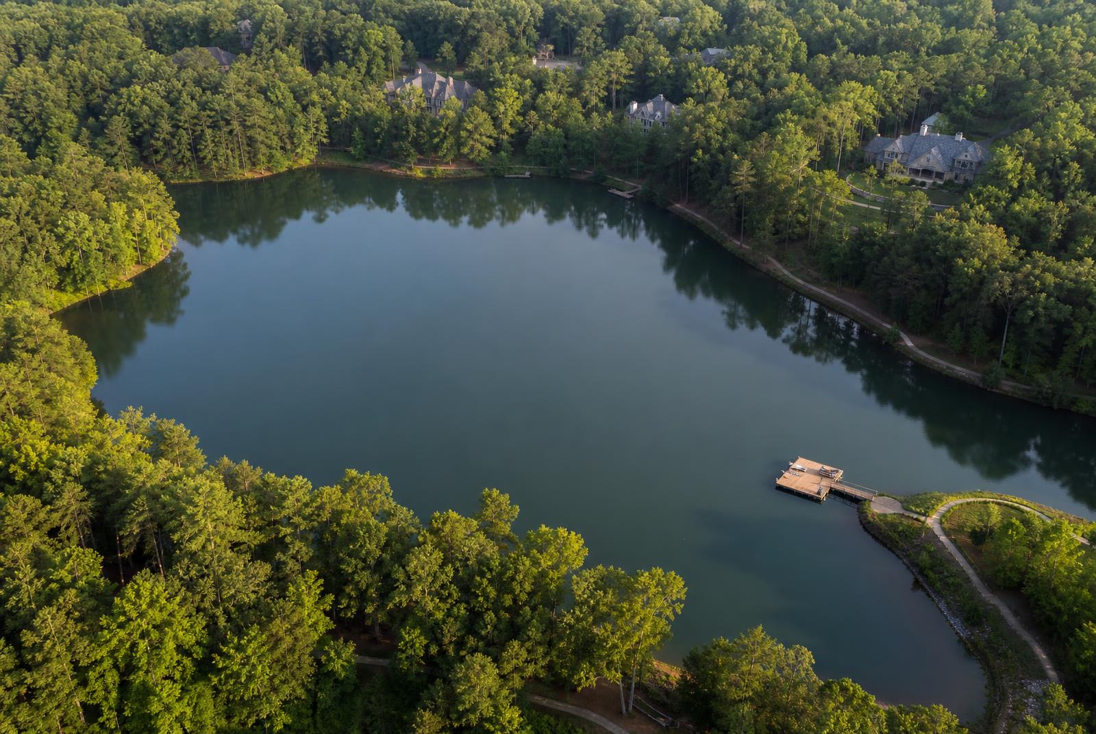 Aerial view of a private community lake, dock and shoreline walking trail