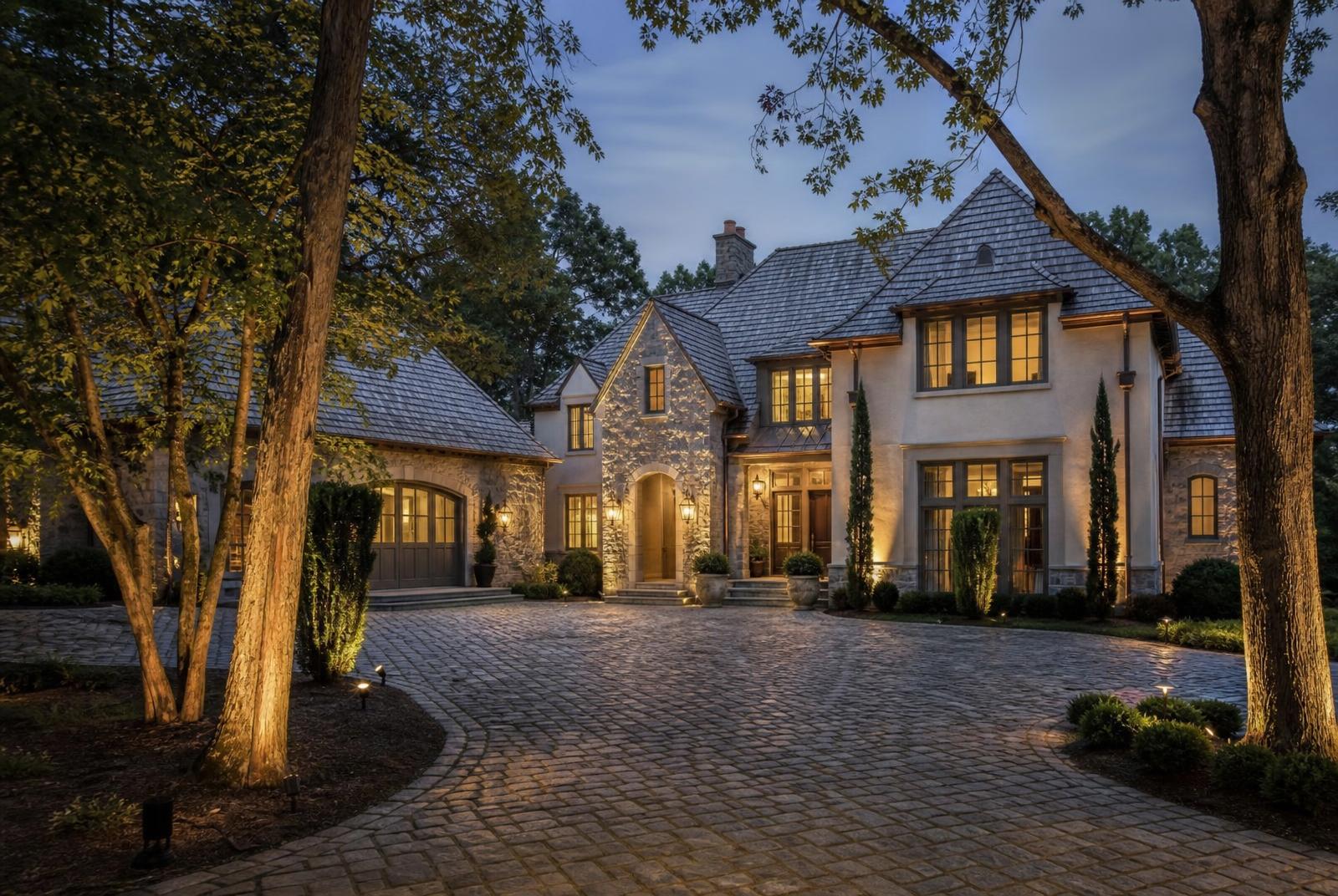 Newly completed French-country custom estate home with cobblestone motor court at blue hour
